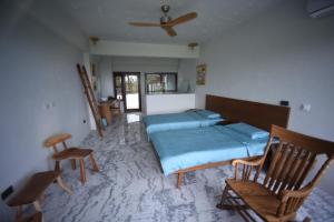 Schlafzimmer mit einem Bett und Stühlen sowie einem Deckenventilator in der Unterkunft Stone Party in Donghe