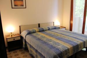 a bedroom with a bed with a blue comforter and two lamps at Appartamenti Aurora in Grado
