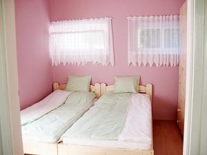 two beds in a small room with pink walls at Apartman Alexa in Ábrahámhegy