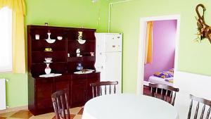 a dining room with a white table and a refrigerator at Apartman Alexa in Ábrahámhegy