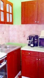 a kitchen with red cabinets and a sink and a microwave at Apartman Alexa in Ábrahámhegy
