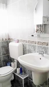 a white bathroom with a toilet and a sink at Apartman Alexa in Ábrahámhegy