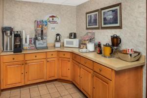 a kitchen with wooden cabinets and a counter top at Super 8 by Wyndham Burlington NC in Burlington