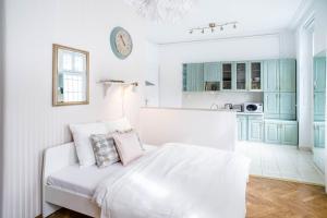 a white room with a bed and a kitchen at Nine Trees Apartment in Budapest