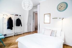 a white bedroom with a bed and a clock on the wall at Nine Trees Apartment in Budapest