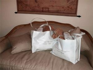 two shopping bags sitting on top of a bed at Garni Villa Tyrol - Adults Only in Merano