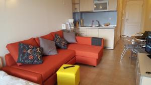 a living room with a red couch and a kitchen at Studio Apartment C32 in Dream Holiday Complex Ravda in Ravda +49 photos