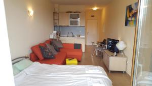 a living room with an orange couch and a kitchen at Studio Apartment C32 in Dream Holiday Complex Ravda in Ravda