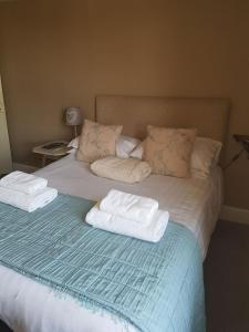 Una cama con toallas y almohadas encima. en George and Dragon Ashbourne, en Ashbourne