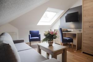 a living room with a couch and a table and a desk at Hotel Ertl in Kulmbach