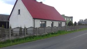 biały dom z czerwonym dachem obok płotu w obiekcie Agroturystyka u Pawła i Asi w Kobylej Górze