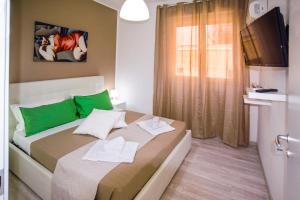 a bedroom with a bed with green pillows and a television at Loft Vista Sul Mare in Letojanni