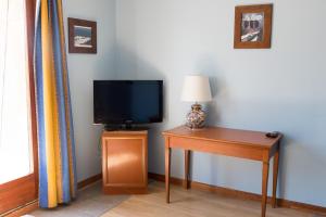 um quarto com uma televisão e uma mesa com um candeeiro em Baccarat Hostel em Nice