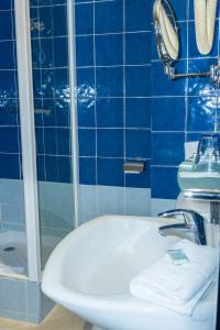 uma casa de banho em azulejos azuis com um lavatório e um chuveiro em Baccarat Hostel em Nice