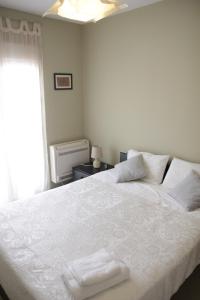 アテネにあるSunny apartment in the heart of Athens Preview listingのベッドルーム1室(白いシーツが敷かれた大型ベッド1台、窓付)