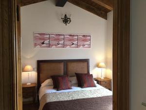 a bedroom with a bed with two lamps and a picture on the wall at AL VIENTO, Alojamiento & Turismo Rural Horcajuelo in Horcajuelo de la Sierra