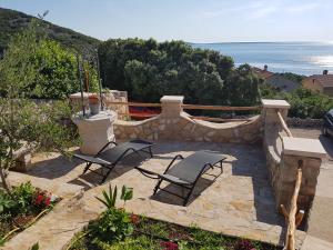 two chairs on a patio with the ocean in the background at Apartmani Ivana in Cres