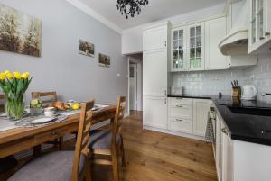 une cuisine avec des armoires blanches et une table en bois dans l'établissement Prosta Apartment Old Town, à Olsztyn