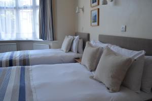 duas camas num quarto de hotel com almofadas brancas em The Riviera Hotel & Apartments - Alum Chine em Bournemouth