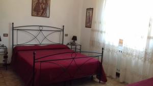 1 dormitorio con cama roja y ventana en Agriturismo Campotondello, en Gavorrano