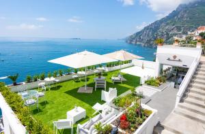 un patio al aire libre con mesas y sillas y el océano en Villa Pietra Santa, en Positano