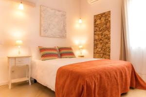 a bedroom with a bed with an orange blanket and two pillows at Cercas Velhas in Sagres +11 photos