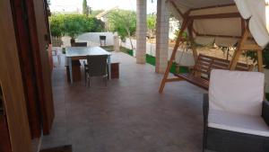 patio con tavolo, sedie e ombrellone di Villa Origano a Santa Maria del Focallo