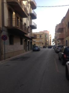 an empty street with cars parked on the sides of buildings at cara sibilla 112 in Marsala