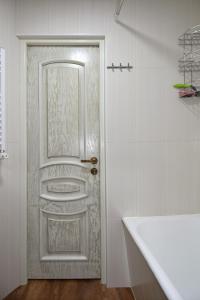 a white door in a white bathroom with a tub at Уютная квартира около медицинского центра Астхик! in Yerevan