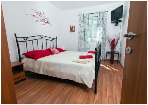 sypialnia z łóżkiem z czerwonymi poduszkami i telewizorem w obiekcie Apartments FRAGOLINA w mieście Donje Selo na Šolti