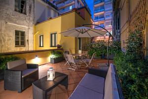 eine Terrasse mit Tisch, Stühlen und Sonnenschirm in der Unterkunft Le Terrazze sul Cortile in Salerno