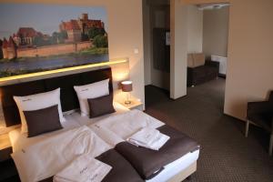 a bedroom with a large bed with a painting on the wall at Hotel Piast przy Zamku in Malbork