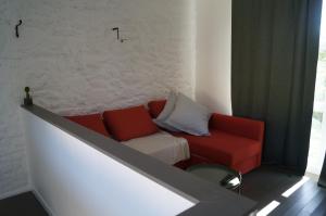 a living room with a red couch next to a wall at La maison d'hôtes Ty Pic in La Vicomté-sur-Rance