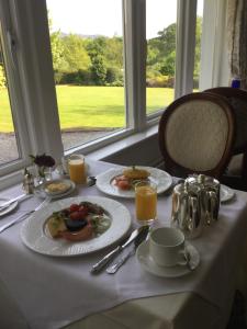 a table with plates of food and orange juice at Lyzzick Hall Hotel in Keswick