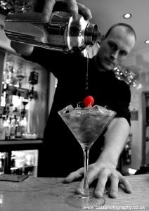 a man pouring a drink into a martini glass at The Riviera Hotel & Apartments - Alum Chine in Bournemouth