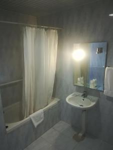 a white bathroom with a sink and a shower at Hotel Conforto Latino in Abrantes