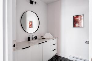 Baño blanco con lavabo y espejo en Maison Saint-Vincent By Maisons & co en Montreal