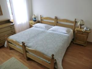 sypialnia z drewnianym łóżkiem i 2 szafkami nocnymi w obiekcie Ajarnola Locazioni Turist w mieście Auronzo di Cadore