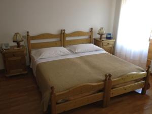 1 dormitorio con 1 cama grande de madera y 2 mesitas de noche en Ajarnola Locazioni Turist en Auronzo di Cadore
