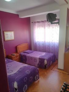 two beds in a room with purple walls at Hotel Conforto Latino in Abrantes