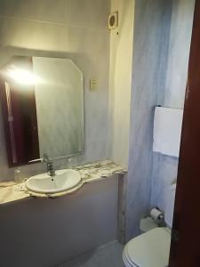 a bathroom with a sink and a toilet and a mirror at Hotel Conforto Latino in Abrantes