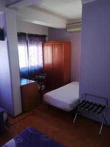 a small room with a small bed and a cabinet at Hotel Conforto Latino in Abrantes