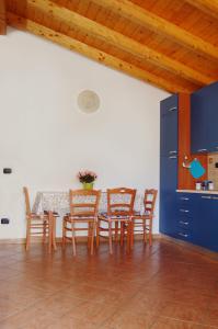 een keuken met een tafel met stoelen en een blauwe kast bij Portorosa Apartments Helene in Furnari