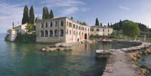 a large building sitting in the water next to a lake at Locanda San Vigilio in Garda