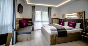ein Schlafzimmer mit einem großen Bett mit lila Kissen in der Unterkunft Pension Willibald in Bad Tölz