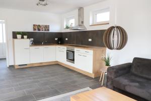a kitchen with white cabinets and a couch in a room at Ferienhaus am Alfsee in Rieste