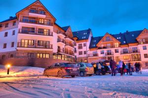 un groupe de voitures garées devant un bâtiment dans l'établissement Aparthotel Cristal Resort Szklarska Poręba by Zdrojowa, à Szklarska Poręba