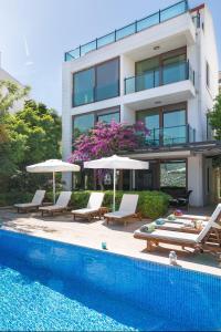 a building with a swimming pool with chairs and umbrellas at Villa Kiki in Kalkan