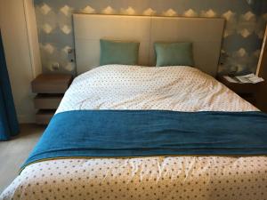 a large bed with a blue blanket on it at Cyrille et Vacances Presqu'ile de la Touques in Deauville +17 photos
