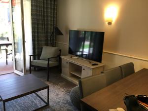 a living room with a flat screen tv and a table at Cyrille et Vacances Presqu'ile de la Touques in Deauville